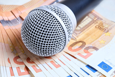 Microphone over euro bills background close up shot. Microphone lies on scattered euro banknotes.の写真素材
