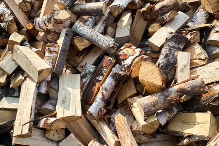 Stack of birch firewood with hand chopping block. Chopped firewood for winter. Lot of firewood - harvesting wood for heating the house. Horizontal photo. Chopped firewood background and textureの写真素材