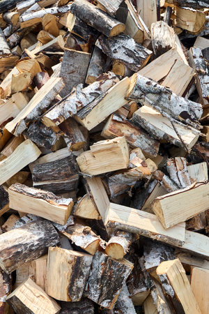 Stack of birch firewood with hand chopping block. Chopped firewood for winter. Lot of firewood -...