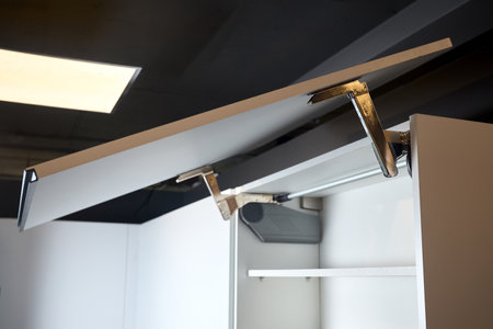 System for bi-fold fronts and facades for kitchen cabinets direct access. Element of contemporary kitchen interior closeup. Opened white horizontal kitchen cabinet sideboard with lifting mechanism.の写真素材