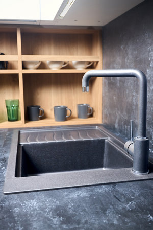 Interior of contemporary green and red kitchen. Luxury modern fitted flat design kitchen with square stoneware sink and tap wooden shelves cupboard sideboard with dish drying cabinet vertical shot.の写真素材