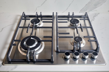 Modern hob gas or gas stove made of stainless steel using natural gas or propane for cooking products on light stoneware countertop in kitchen interior, with copy space.の写真素材