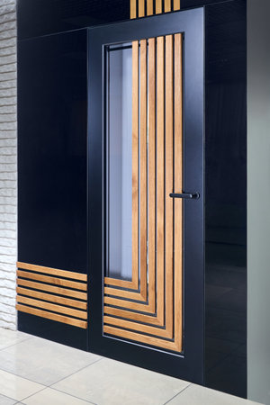 Modern interior design detailing. Aluminum door with vertical and horizontal wooden slats and glass parts made of aluminum profiles.の写真素材