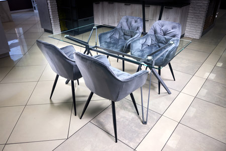 Modern apartment kitchen dining room design. Glass table, interior decor, four velvet gray armchairs on tiled floorの写真素材