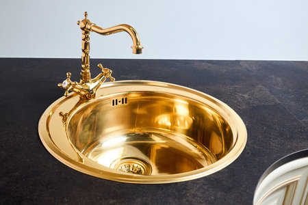 Kitchen luxurious interior with golden brass round sink basin and faucet double tap mixer in contemporary modern design with stone marble stoneware countertop.の写真素材