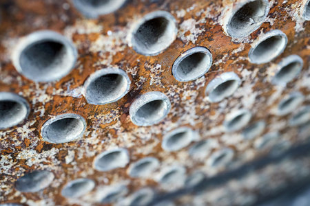 Tube sheet plate of heat exchanger or boiler closeup selective focus texture industrial background with insoluble hard mineral deposits salts scale welding seams and corrosion. Trypophobia concept.の写真素材