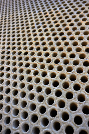 Tube sheet or plate of heat exchanger boiler selective focus shot at an angle closeup texture...