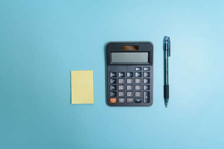 A notepad, calculator, and a pen on desk.の写真素材