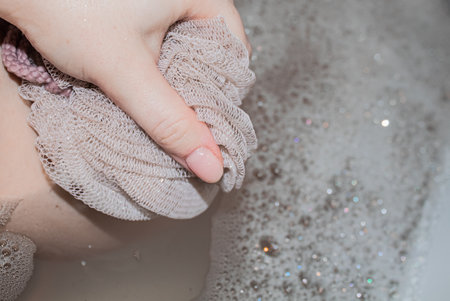 Beige washcloth in womens hands close-up while washingの写真素材