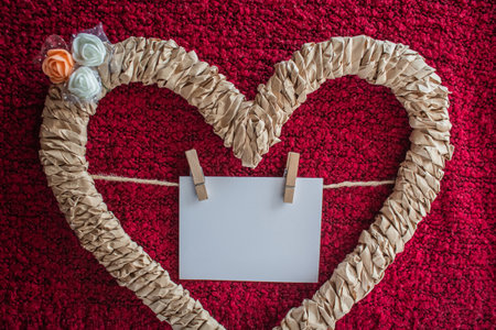 Braided heart decorated with flowers with a card on a threadの写真素材