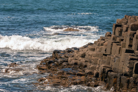 The ocean is calm and the rocks are jagged. The water is a deep blue color. The rocks are scattered...