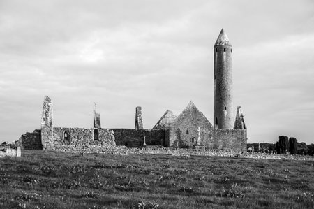 A large tower stands in the middle of a field. The tower is surrounded by a graveyard with several gravestones. The scene is quiet and peaceful, with the towerの写真素材