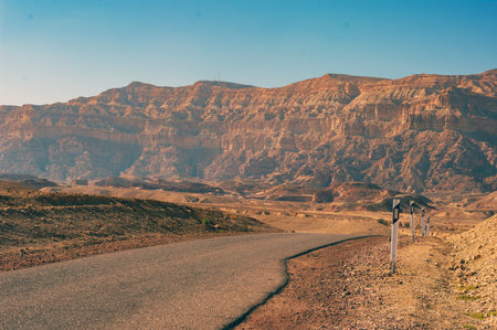 A road in the desert with a post on the side. The road is empty and the sky is clearの写真素材