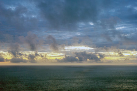 The sky is cloudy and the ocean is calm. The clouds are low and the sun is settingの写真素材