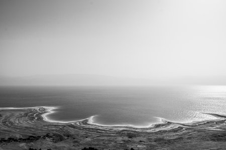 A calm, still body of water with a white horizon. The sky is clear and the sun is shining brightlyの写真素材
