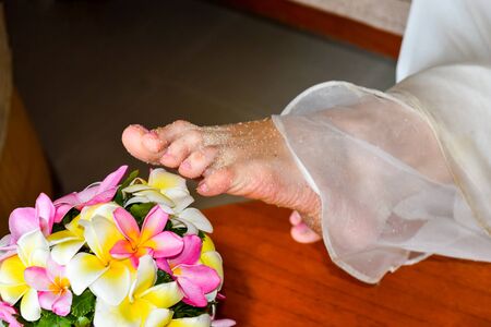 Seychelles, Mahe island. After of walking in beach, bride reaches the bouquet of exotic flowers with her sandy feetの写真素材