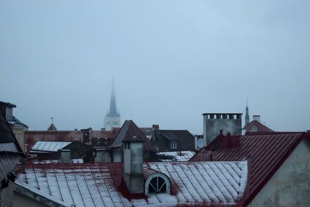 Oldtown roofs in Tallinn, Estonia. The fog, drizzle and partially visible church tower in the background gives a sense of mysteryの写真素材