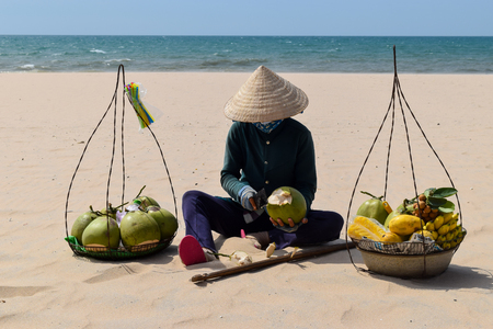 Beach Fruit Salesman Resting on the Sand in Vietnam. He is selling Coconuts, Bananas and other exotic fruitsの写真素材