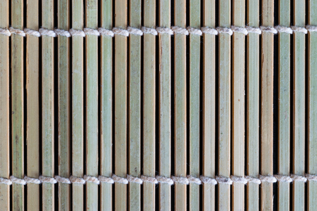 Old mat made by natural bamboo sticks and tied up between each other with the white ropeの写真素材