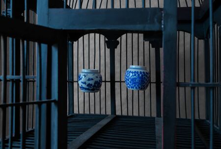 Vintage and old wooden bird cage with water cups from porcelain and Chinese paintings on itの写真素材