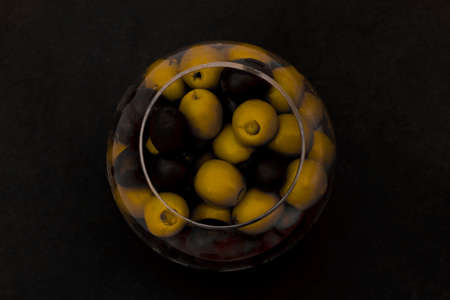 Black and green olives in glass jar view from the top on the black backgroundの写真素材