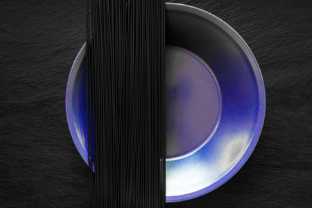 Black Spaghetti noodles on purple plate which placed on back stone surfaceの写真素材