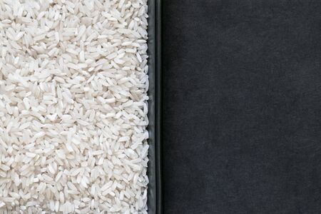 Rice grains in the plate and black background with free spaceの写真素材