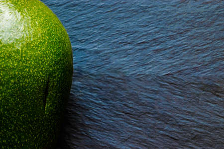 Full green avocado fruit on super blurred blue stone background surfaceの写真素材