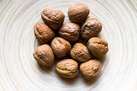 Whole Walnuts on soft brown bamboo plate background surfaceの写真素材