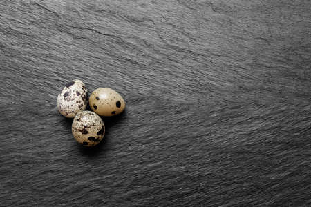 Three quail eggs on black stone background surface with free spaceの写真素材