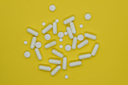 Bunch of different forms white medication pills on yellow background surface
