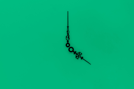 Abstract composition of very old and vintage black clockwise casting blurred shadow on green background surfaceの写真素材