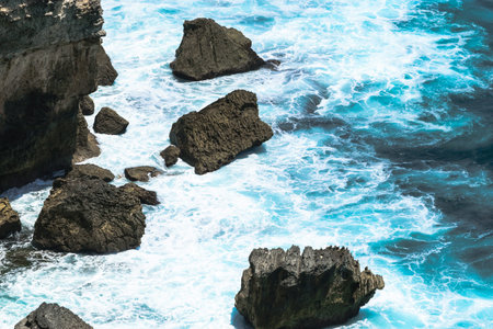 Blue Indian ocean washing the cliff and beach with huge rocks in Bali, Indonesia