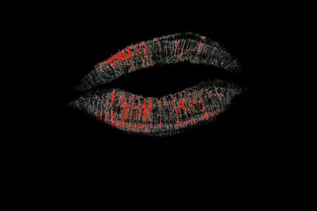 Black lips with flowing pink lipstick prints on black background surfaceの写真素材