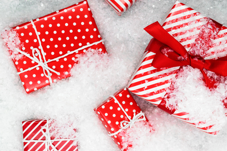 Various size wrapped in red paper with ornament Christmas gift boxes on artificial snowの写真素材