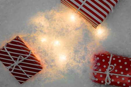 Background surface of white artificial snow illuminated by white light from inside and red gift boxesの写真素材