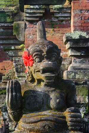 Traditional Bali island stone sculpture of naked woman and decorated with local red flower blossomの写真素材