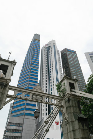 Singapore - 14 OCT 2018. Business district with modern skyscrapers, bridge and cloudy sky. Beautiful contrast of grey buildings facade and blue windowsのeditorial素材