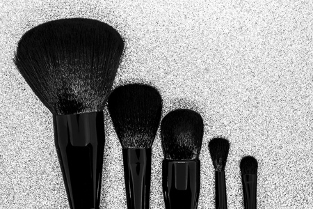 Black makeup brushes on shiny silver background surfaceの写真素材