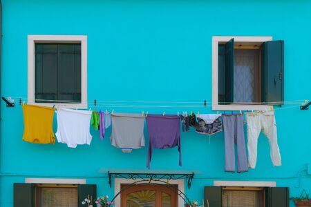 Fresh washed laundry hanging on the blue house in Burano island, Veniceの写真素材