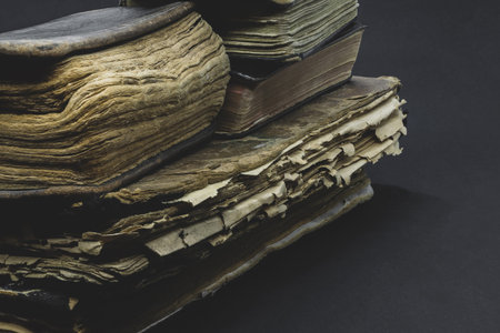 Pile of old, aged, dusty and dark books on black background with copy space