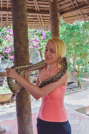 Woman with scary face holding snake in Vietnam village. Picture is noisy and main subject has motion...