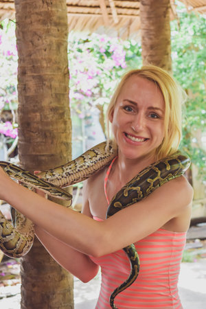 Woman with scary face holding snake in Vietnam village. Picture is noisy and main subject has motion...