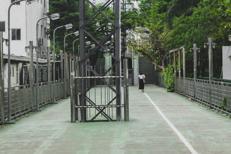 Urban lifestyle concept. Lonely woman walking in empty green pedestrian path in background of green...