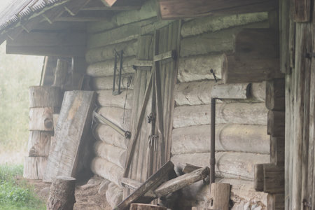 Old wooden barn covered with autumn morning fog with copy space. Image looks noisy and shaky due to...