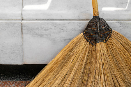 Abstract background of straw broom placed near white marble wall with copy space