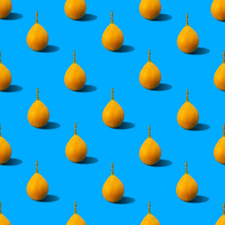 Colorful and summer time background pattern illustration of yellow fresh passion fruits (sweet granadilla) casting hard shadow on blue surface. Minimal summer food conceptの写真素材
