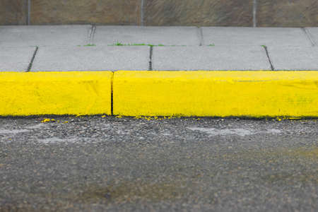 Sidewalk painted with yellow paints and concrete path with road background with copy spaceの写真素材
