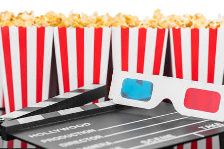 Cinema, movie, leisure and theater concept. Popcorn boxes with white and red stripes full of sweet with caramel popcorn, 3D glasses and clapperboard on black reflective backgroundの写真素材