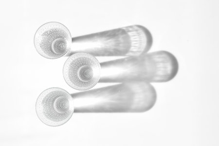 Fancy retro drinking glasses casting hard shadows on background. Retro vintage style. Black and white imageの写真素材